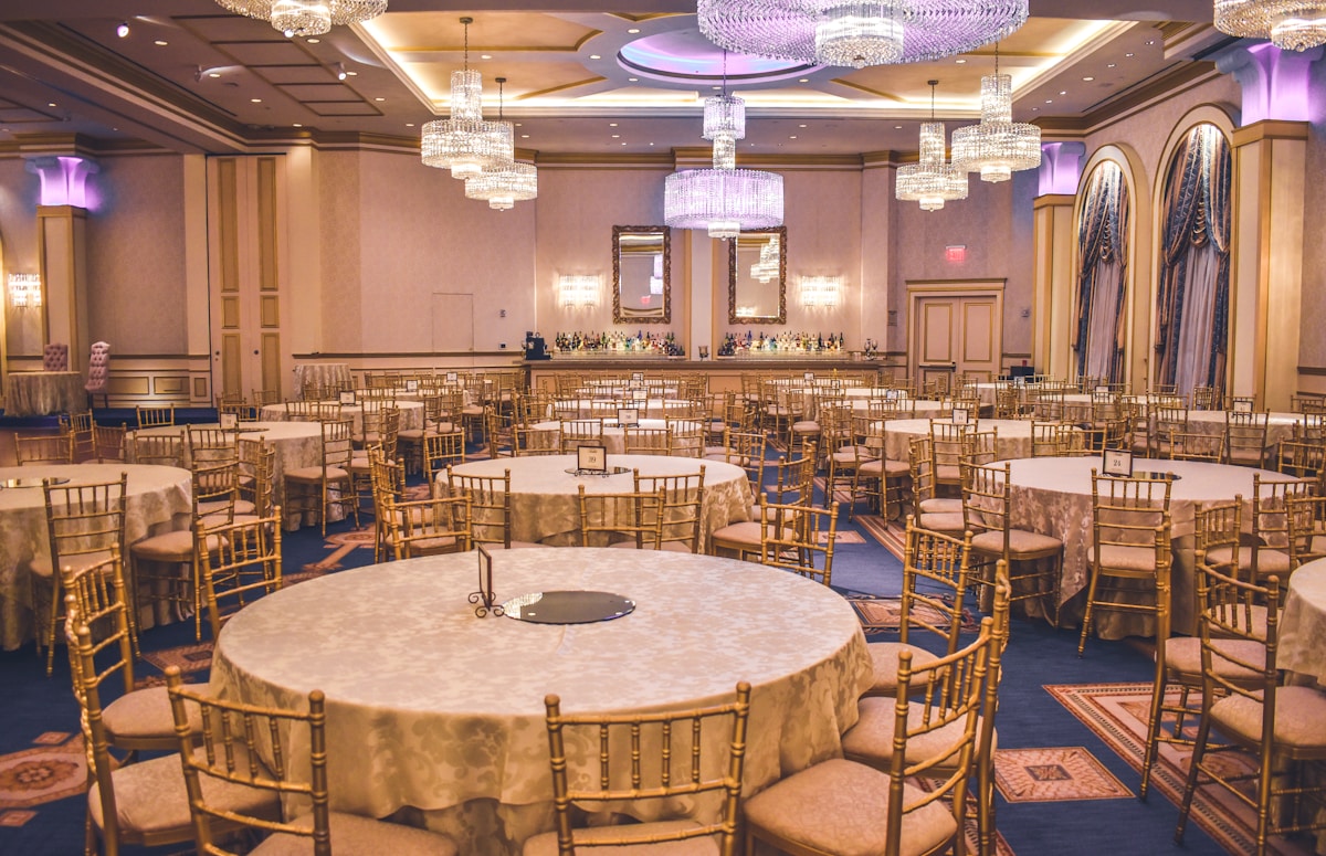 A spacious event hall with elegant table settings and warm overhead lighting